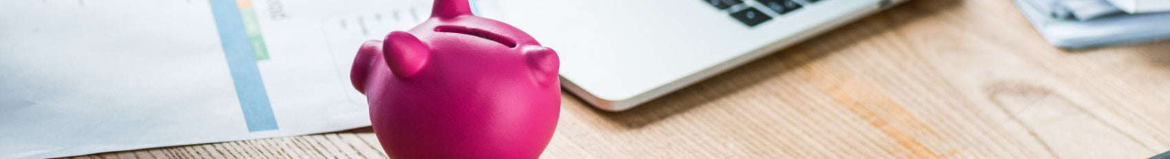 pink piggybank on a wooden table next to a laptop for business lawyer fees